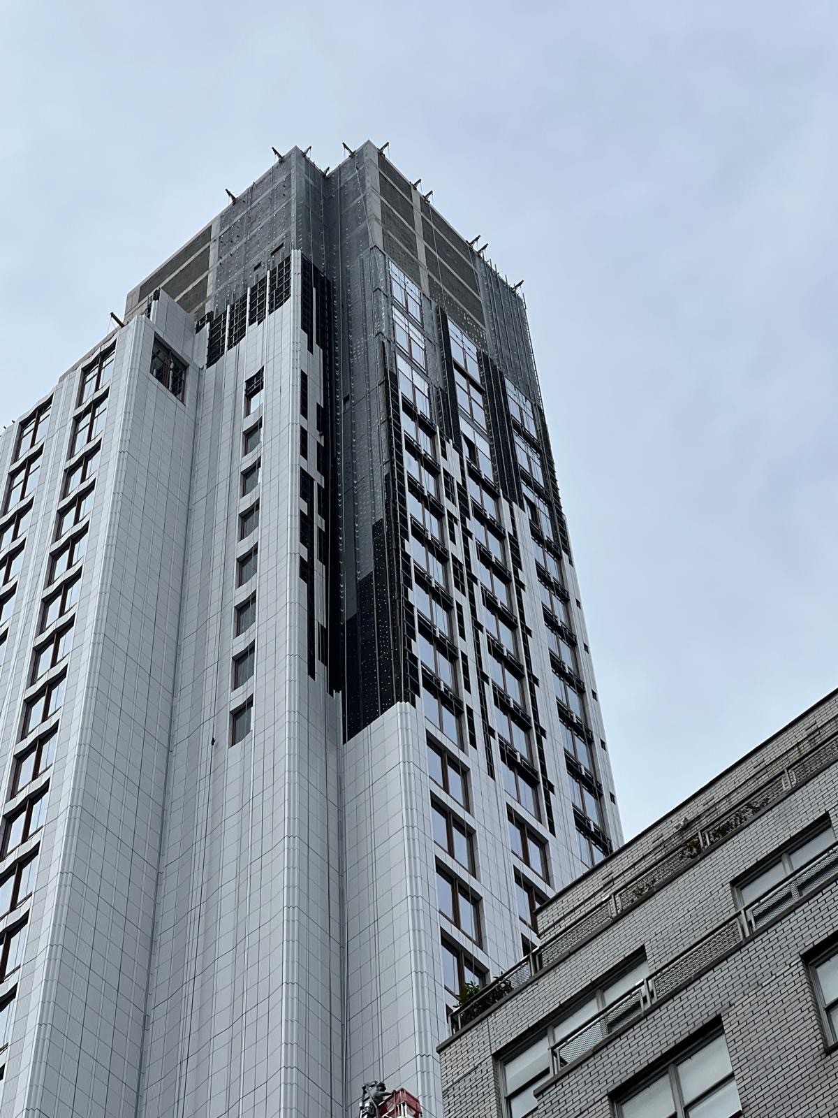 1299 3rd Avenue stone facade viewed between neighboring buildings