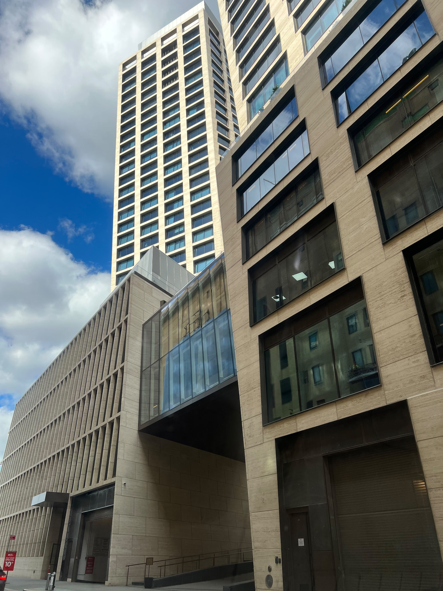 500 West 18th Street stone facade and glass bridge viewed from street level